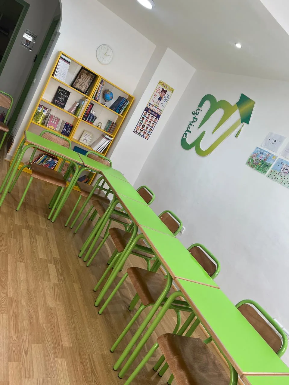 Salle de cours collective Wizaide à Marrakech : longue table verte, chaises vertes et logo Wizaide en relief sur le mur blanc.
