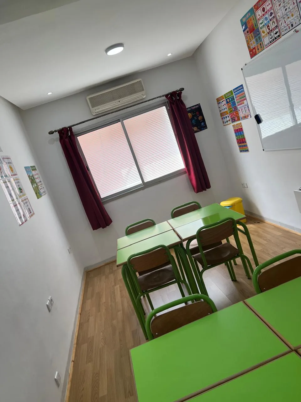 Petite salle de cours individuel Wizaide à Guéliz : tables vertes, climatisation et rideaux bordeaux pour un cadre intime.